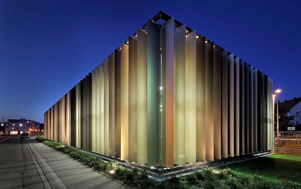 Bewegliche Sonnenschutzfassade aus imposant hohen und vertikal angeordneten Aluminiumlamellen